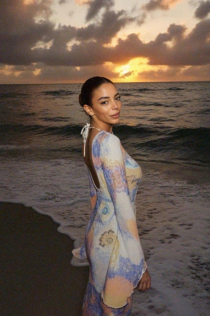 Luna is shown in profile on a sunset beach, wearing a floor-length pastel tie-dye dress with a deep open back.